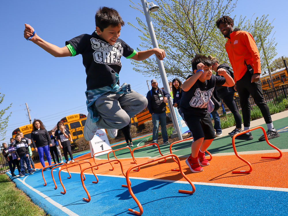 Children jumping over track obstacles.